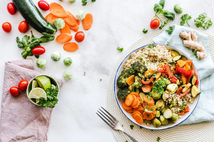 A grain and roast vegetable bowl with tomatoes, herbs and lime