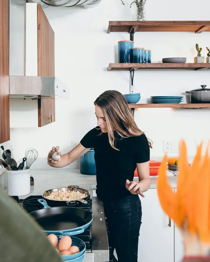 A creator cooking at the stove in a bright home kitchen