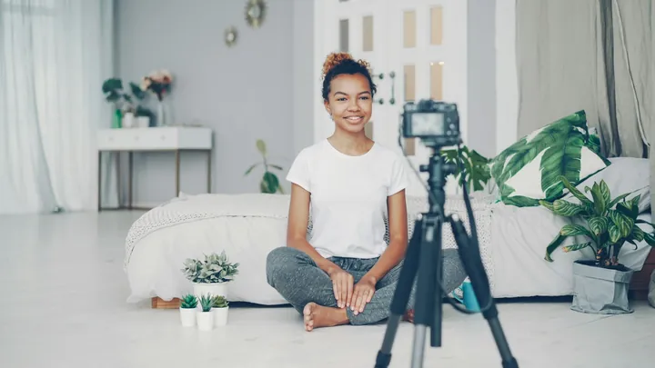 A creator sitting on her living room floor, talking to a camera on a tripod