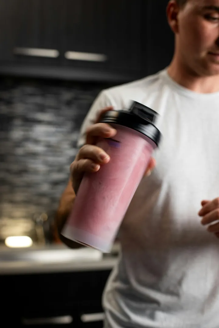 A creator holding a pink shaker bottle in his kitchen