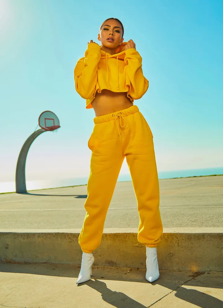 A woman in a yellow tracksuit on a basketball court under a blue sky, beside a Selado certificate. Brands and people shown are fictional.