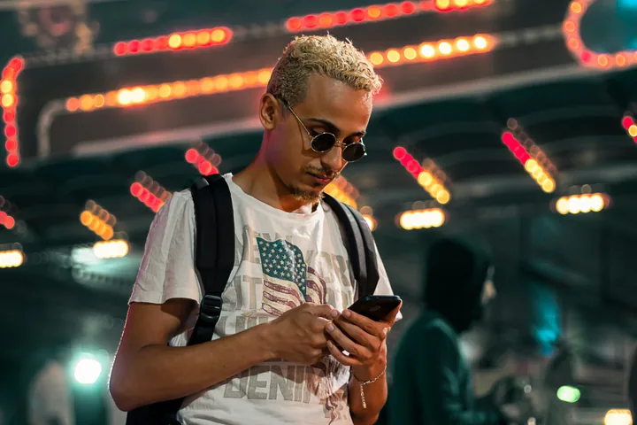 A man checking his phone among city lights at night, with the Selado resubmit screen on a phone beside him. Brands and creators shown are fictional.