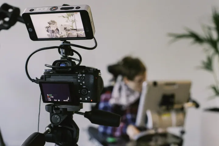 A camera on a rig filming a creator at a desk