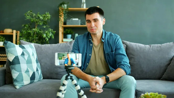 A creator on a couch filming himself on a phone tripod