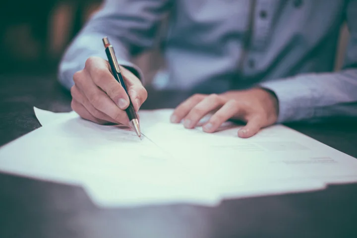 A reviewer in a blue shirt signing papers with a pen